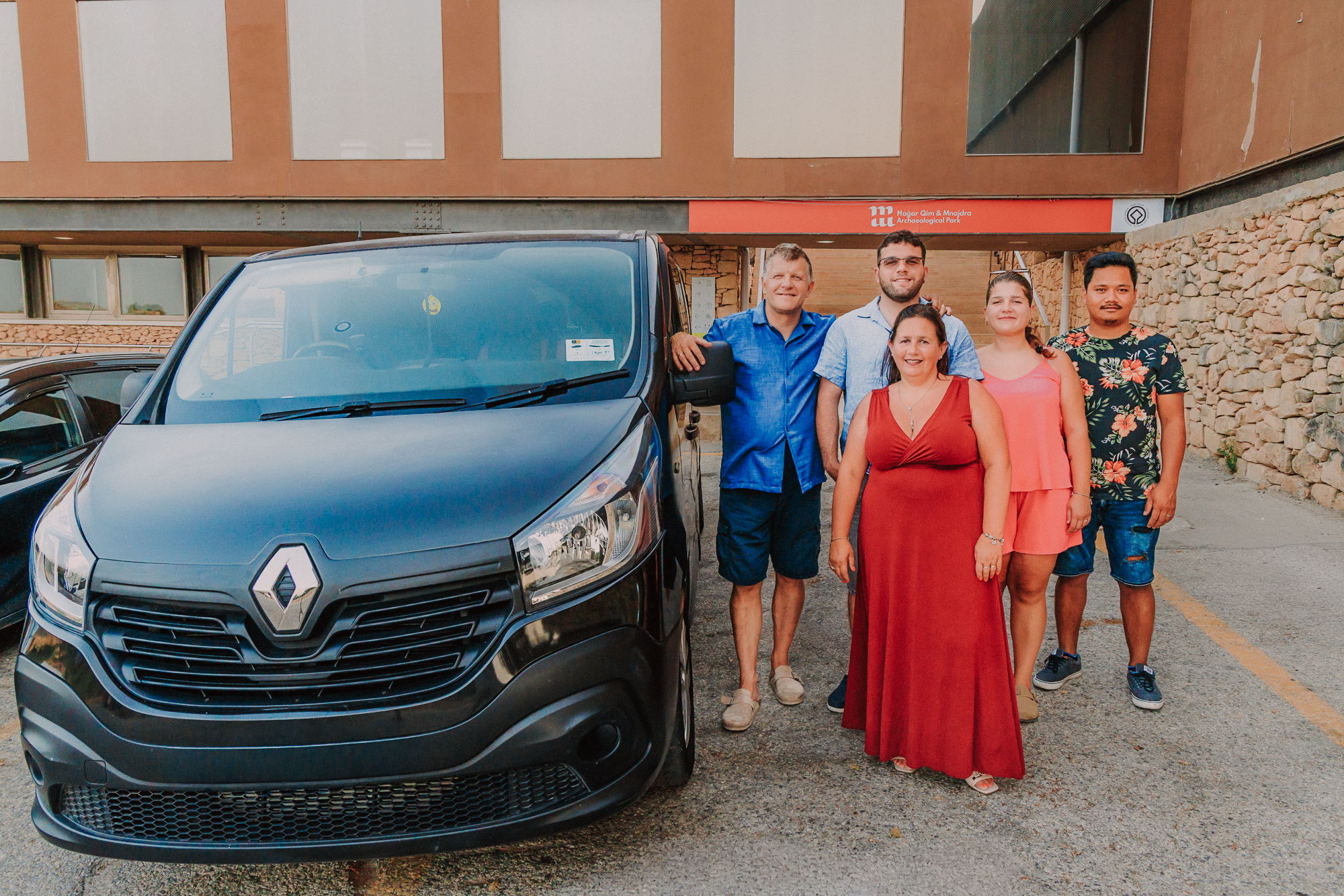 The Bozic family standing together beside their van